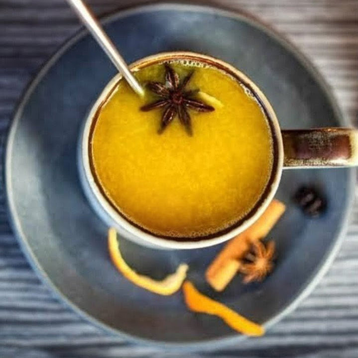 Hot beverage in a mug with star anise and cinnamon on a wooden surface
